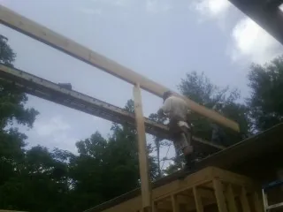 Carpenter setting a ridge beam over a new addition frame — Ice Dam Removal by Roofing Brothers in Dimondale