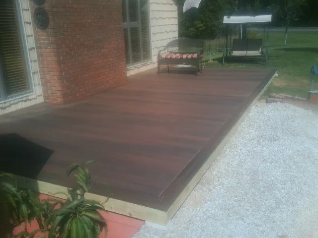 Freshly stained wood deck built against a brick home in Dimondale
