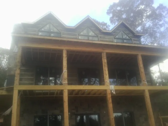 Dormers and porch framing on a large log home under construction — Roof Coating work by our crew in Dimondale