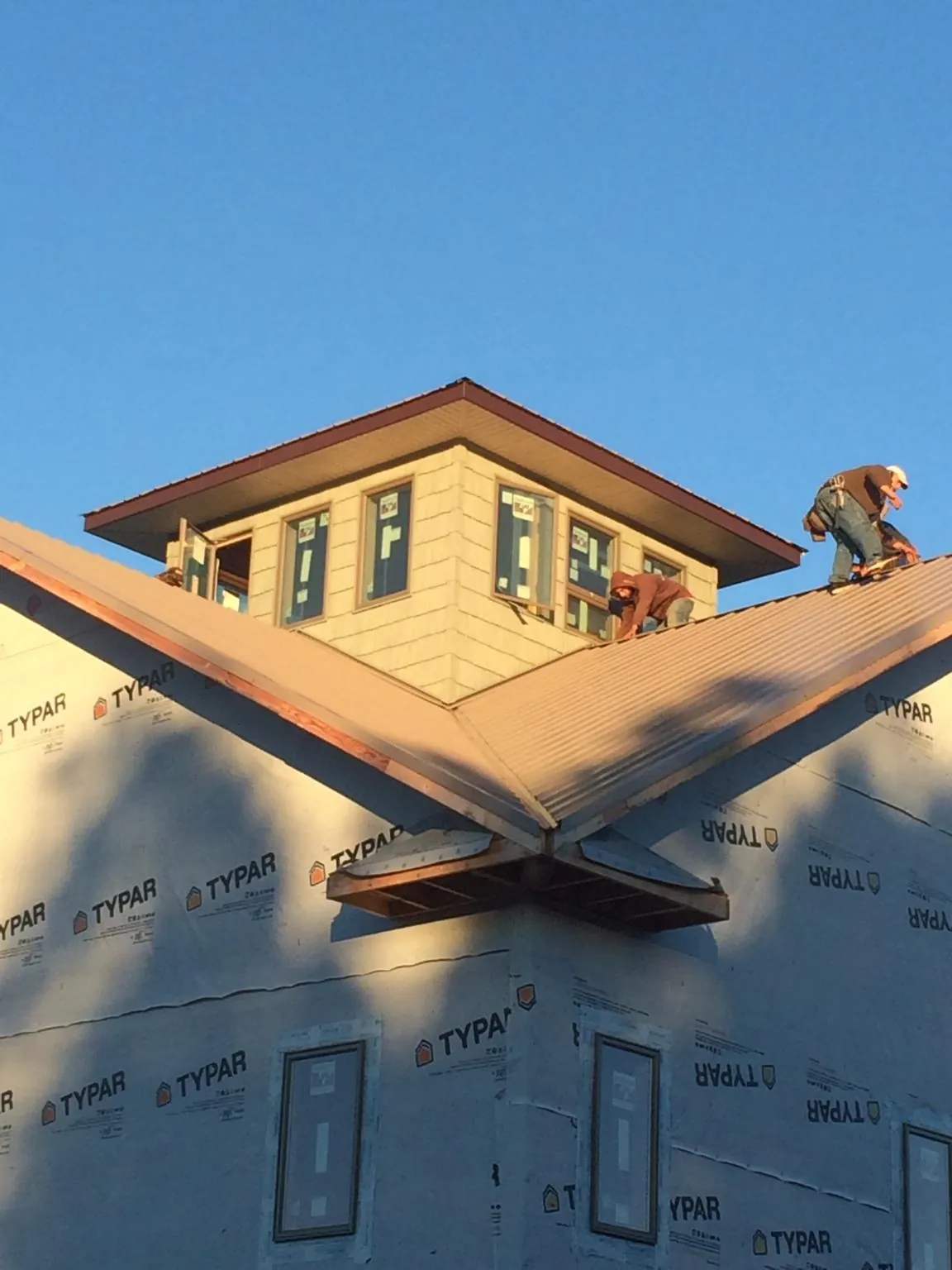 Roofers working around a rooftop cupola on a new metal roof at sunset — Roof Waterproofing in Dimondale by Roofing Brothers